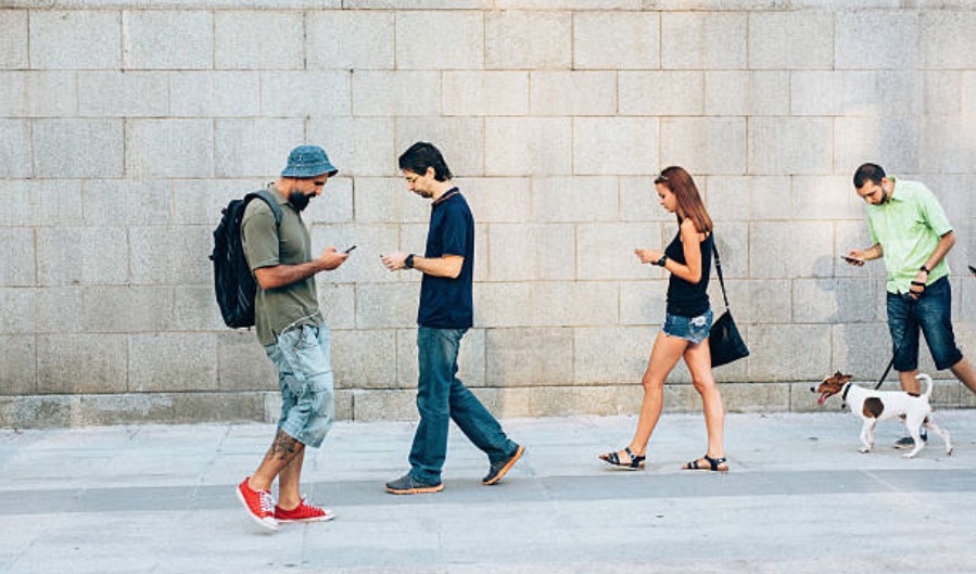 People walking in the street, looking at their mobile phones